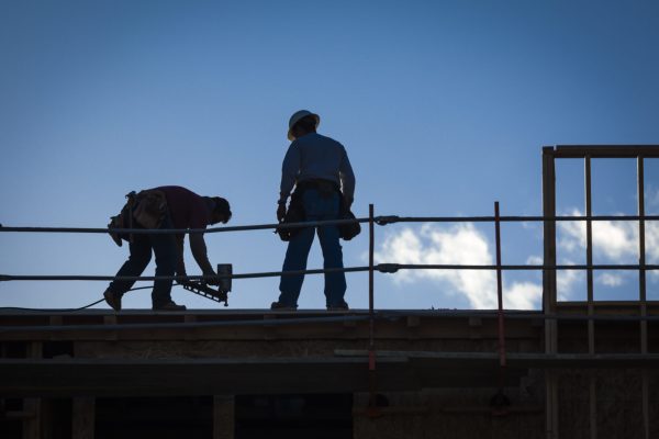 Construction Workers Silhouette on Roof of Building.