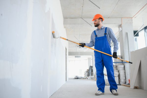 painter man painting the wall, with paint roller.